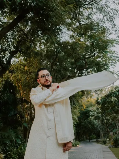A groom's portrait amidst the lush greenery of a Pushkar resort, capturing a moment of quiet anticipation.