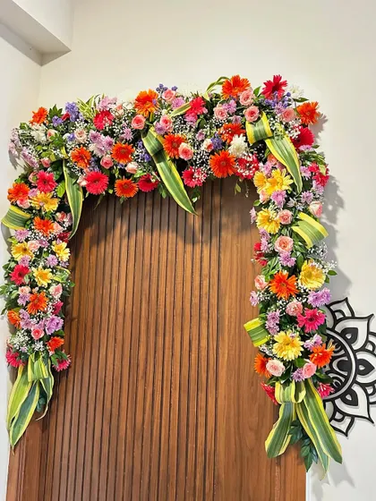 An intricate and colorful floral arch created over a doorway inside the house. We use a mix of fresh, vibrant flowers to bring life and beauty to your indoor spaces.