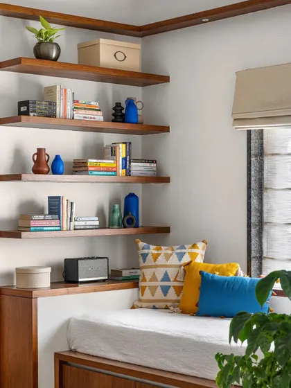 In this family lounge, we designed a platform seat for TV viewing with storage underneath, complemented by floating library shelves for a cozy reading corner.