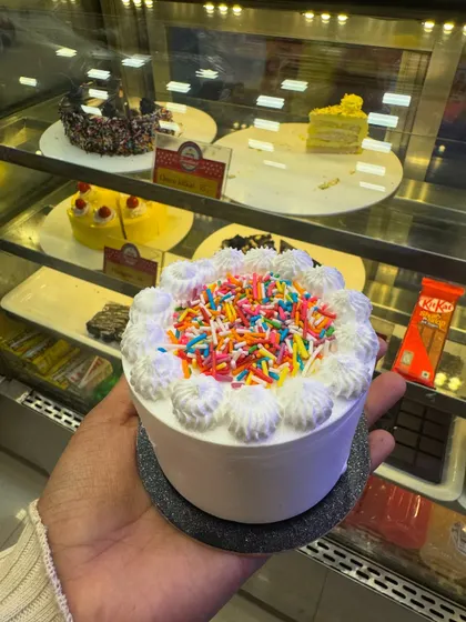 A fun and festive mini cake topped with a generous amount of colorful sprinkles. It's a simple cake that screams "celebration" and is sure to bring a smile to anyone's face.