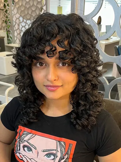 A curly shag for Swathy. This cut is perfect for adding volume and movement to medium-length curly hair.