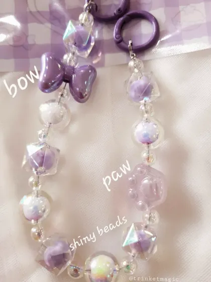 This purple bag charm features shiny, geometric beads, a glossy bow, and a paw print charm, making it perfect for dog lovers with a kawaii aesthetic.