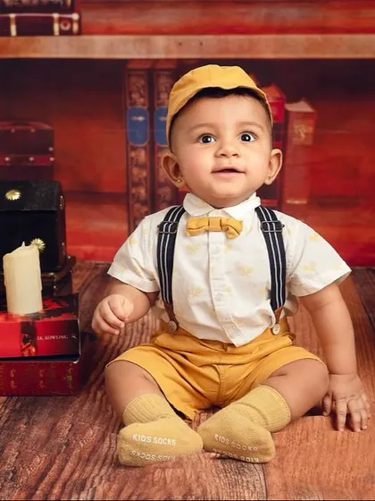 This little wizard is ready to cast a spell of cuteness. The suspenders, bow tie, and props create an authentic and adorable Harry Potter inspired scene.