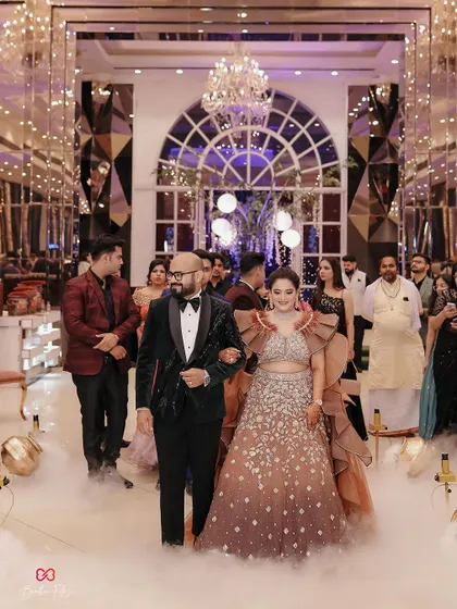 The couple makes their grand entrance at the engagement party, walking hand-in-hand through a path of low fog, looking every bit the fairy-tale couple.