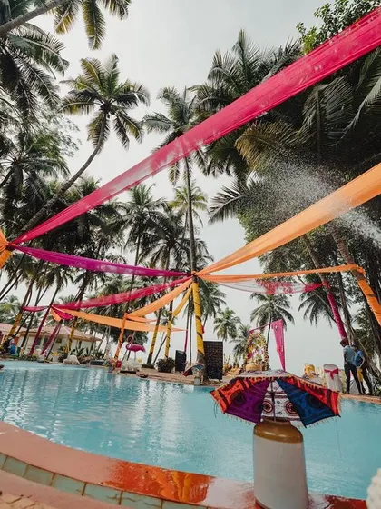 A poolside view of our Haldi Carnival Extravaganza, where colorful drapes stretch across the pool, creating a ceiling of vibrant hues.