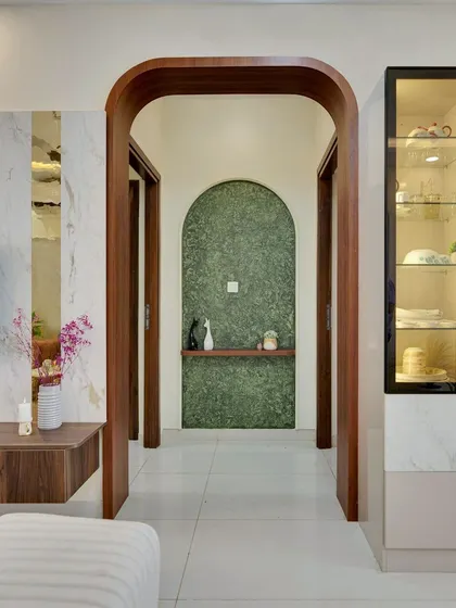 A beautiful arched wooden entryway frames a passage with a green textured wall, creating an elegant and inviting transition between spaces.