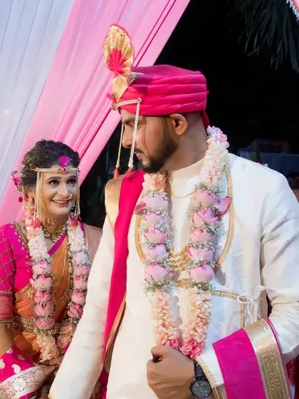 The couple shares a happy look as they walk together after a ritual, framed by the beautiful pink and white decor.