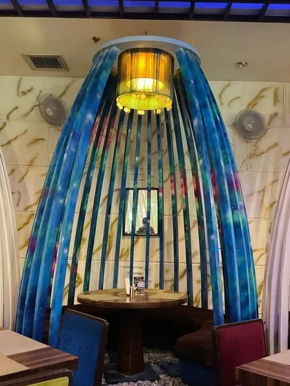 A front view of the painted seating pod, showing how the colors complement the restaurant's interior lighting and decor. It turns a simple seating area into a piece of art.