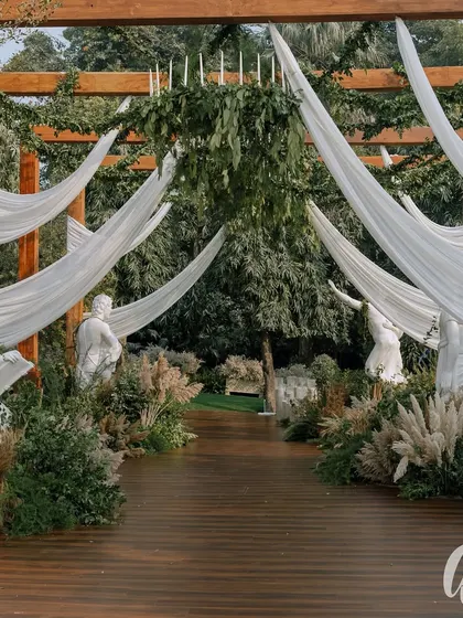A view of the elegant tent structure, with its draped fabric and surrounding greenery. The design seamlessly integrates the indoor comfort with the beauty of the outdoor setting.