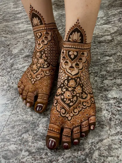 A full-coverage bridal feet mehendi with a beautiful blend of traditional patterns, including lotus flowers and jaali work.