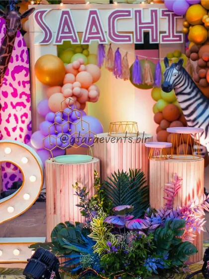 A close-up of the vibrant jungle stage, highlighting the light-up number "2", the custom "Saachi" sign, and the colorful balloon arrangements.