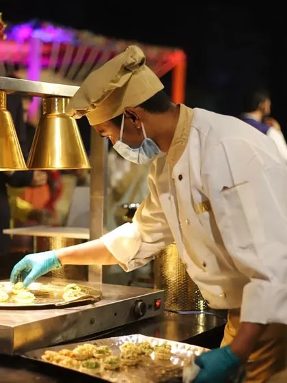 A chef at one of my live food counters, carefully preparing appetizers under heat lamps to ensure every piece is served warm and fresh.
