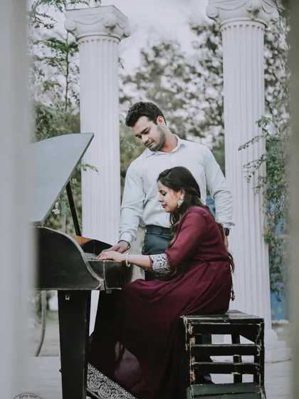 Using props like this grand piano adds a touch of classic romance to a pre-wedding shoot. The groom looks on as his fiancée plays, creating a story-driven and elegant photograph.