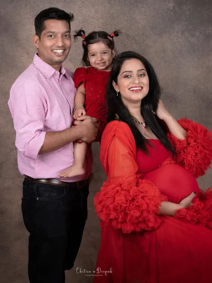 A beautiful family portrait filled with smiles. The matching red outfits for mom and daughter are an adorable touch.
