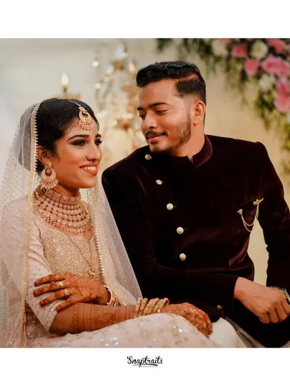 A classic portrait of the bride and groom, seated together and sharing a look of love. The soft lighting and elegant decor create a romantic ambiance.
