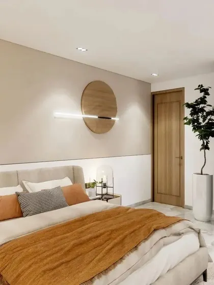 This view shows the full room, including the simple, handleless wardrobe that blends into the wall, making the space feel larger. The indoor plant adds a touch of nature.