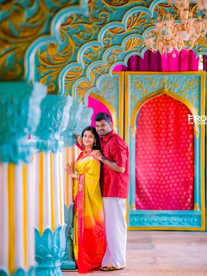 A beautiful portrait of a couple in colorful traditional wear, framed by vibrant, decorative architecture. This shot is full of life and joy.