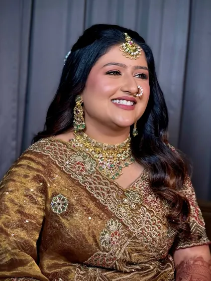 A happy bride in a stunning bronze and red lehenga, her soft glam makeup perfectly complementing the warm tones of her outfit.