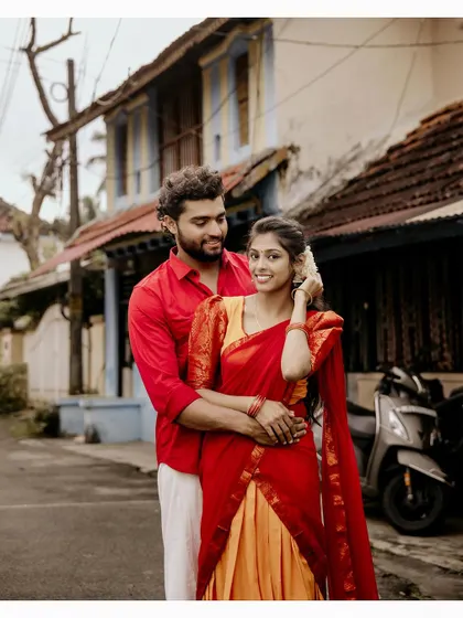 A sweet couple portrait in a village street, with the groom embracing his partner from behind.