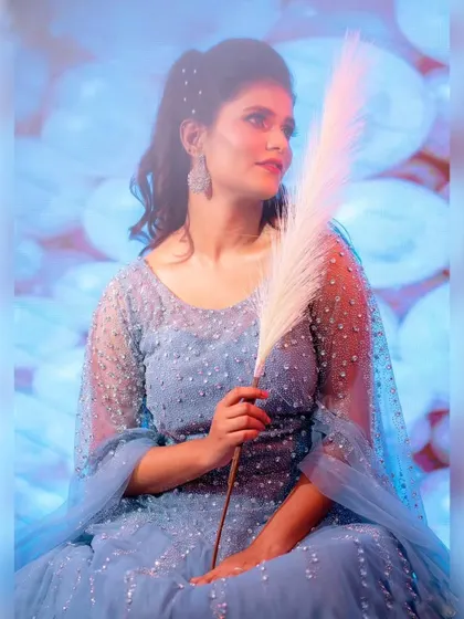 A whimsical and dreamy portrait. The soft lighting and the bride's pose highlight the ethereal quality of this sparkling blue ball gown.