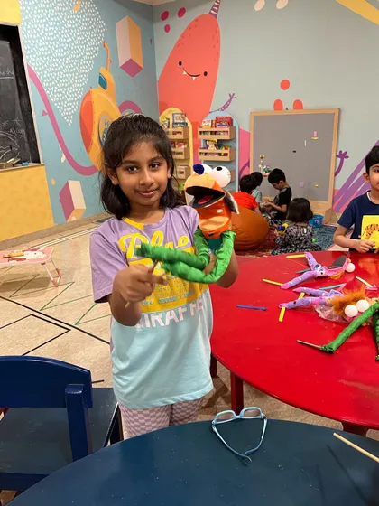 Proudly showing off a completed hand puppet. This activity not only teaches crafting skills but also gives each child a character for our drama sessions.
