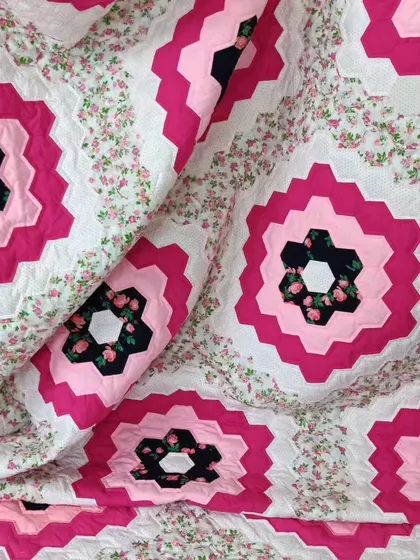 A close-up of a "Grandmother's Flower Garden" quilt, showing the quilting on the hexagonal pieces.