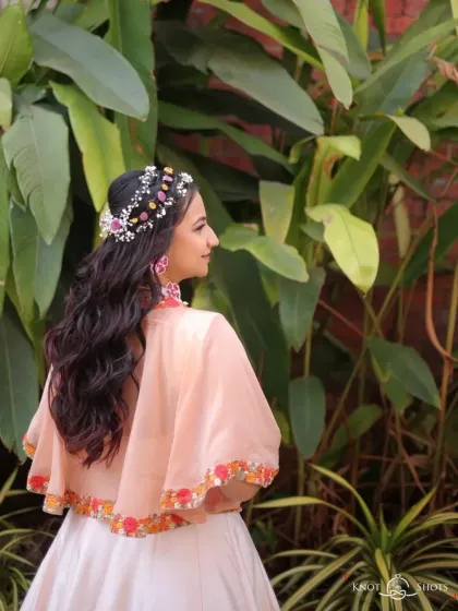 A whimsical and romantic hairstyle for a Haldi carnival. This look features soft waves adorned with a custom floral and beaded headpiece, creating a beautiful bohemian vibe from the back.