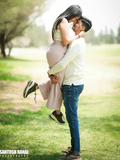 A joyful and energetic outdoor shot of the groom lifting his partner in a grassy field.