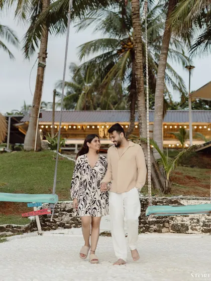 A candid moment of the couple walking hand-in-hand at a beach resort in Ko Samui, Thailand, with beautiful palm trees in the background.