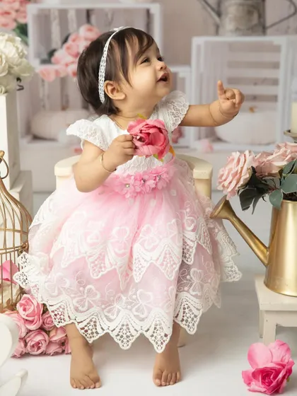 Looking up in wonder. This candid shot captures a moment of curiosity amidst the beautiful floral and white-washed wood backdrop of her cakesmash set.