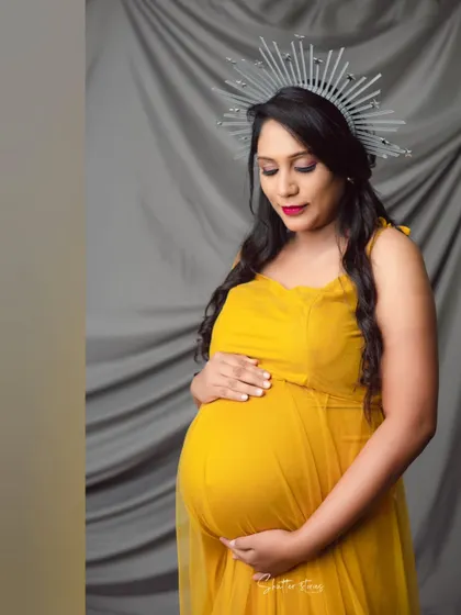 A close-up portrait focusing on the serene expression of the mom-to-be, her hand gently resting on her bump.