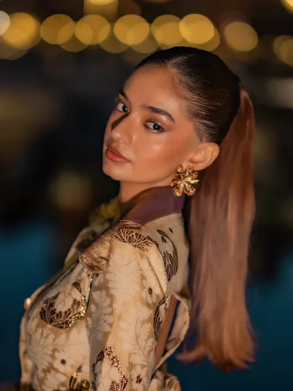 A beauty shot of Anushka from the Nespresso event, highlighting the sleek ponytail and statement floral earrings.