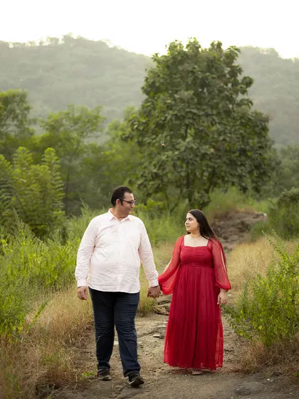 A couple walks hand-in-hand through a rustic, natural trail during their pre-wedding shoot, symbolizing the start of their journey together.