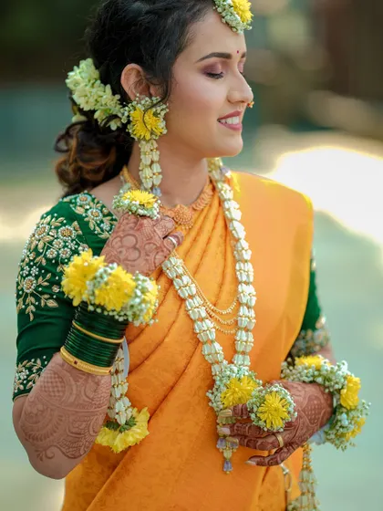 A candid moment of the bride during her Haldi ceremony. Her natural smile and the details of her floral jewelry make this a stunning portrait.
