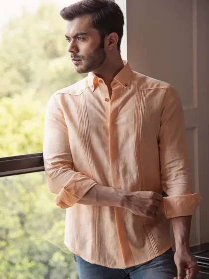 A pastel peach linen shirt with pintuck details. The quality of the linen and the fine craftsmanship are evident in this comfortable and stylish piece.