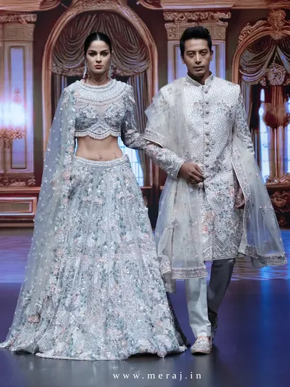A full-length view of the off-white couple's attire on the runway. The groom's sherwani, with its floral details, perfectly complements the bride's ethereal lehenga.