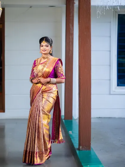 A full-length view of a gorgeous engagement look. The gold and magenta Kanchipuram saree is draped in a classic style, creating an elegant and timeless silhouette.
