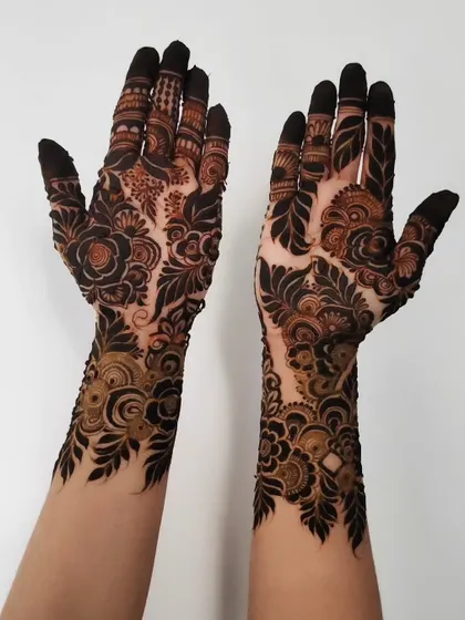 A bold and beautiful design with dark, leafy patterns covering the hands and arms.