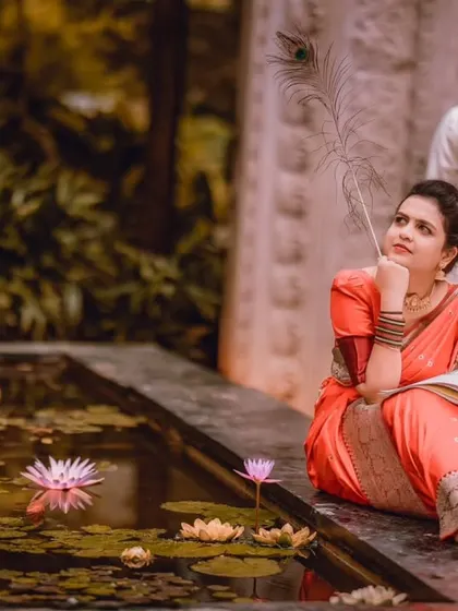 A poetic and thoughtful portrait by a lily pond. The use of a peacock feather as a prop adds a touch of traditional symbolism and artistry.