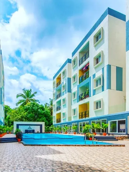 The central courtyard and swimming pool area of a group housing project. The use of blue and yellow accents on the building facades adds a playful and vibrant character to the community space.