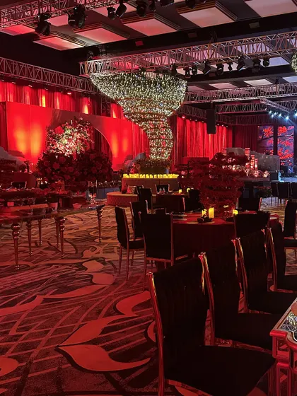 A wide view of the red-themed Sangeet, showing the central floral tornado, velvet-draped tables, and dramatic red lighting that enveloped the entire ballroom.