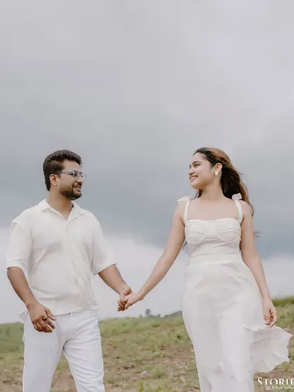 A romantic walking shot of a couple in all white against the backdrop of the rolling hills of Udaipur.
