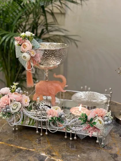 This exquisite hamper is a true style statement. It features an intricately designed silver bowl and other decorative items on a mirrored tray, accented with a peach-coloured elephant and soft pink florals.