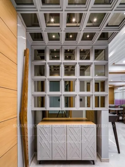 A unique pooja unit or display cabinet with a grid of mirrored niches. This design is perfect for showcasing idols or decorative items in a modern way.