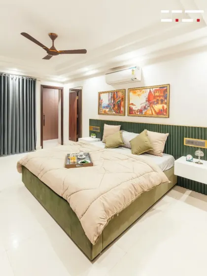 This bedroom combines a rich, green velvet-fluted headboard with warm, colorful artwork. The floating white nightstands and soft bedding complete this look of modern luxury.