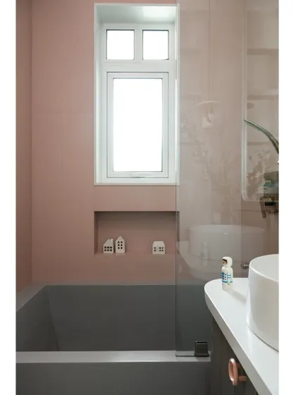 A custom-made grey bathtub is set against soft pink fluted tiles in this daughter's bathroom. The design is a perfect blend of her favorite color with a sophisticated, modern aesthetic.