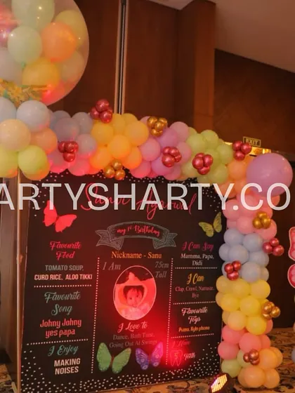 A creative milestone board designed like a chalkboard, sharing fun facts about the birthday girl, framed by colorful balloons and a butterfly prop.