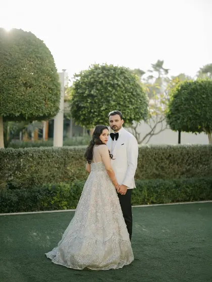 A chic and modern portrait of Roha and Moin in Dubai. The clean lines of their outfits and the manicured gardens create a sophisticated, contemporary look.