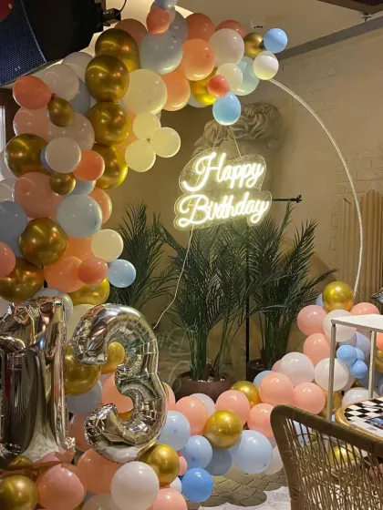 A fun and colorful setup for a 13th birthday. This decor uses a lit ring backdrop with a pastel balloon arch and large silver foil numbers to celebrate becoming a teenager.
