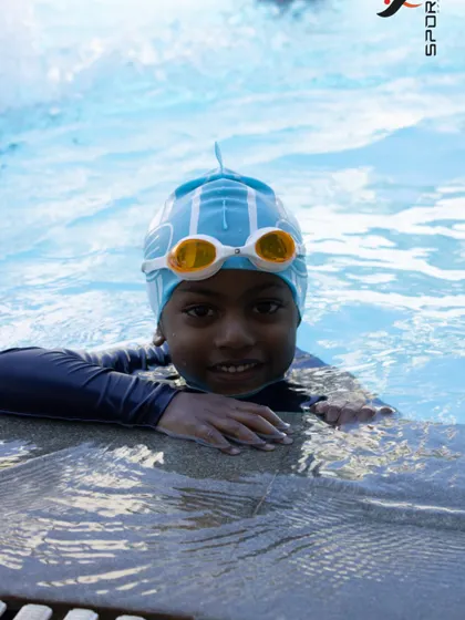 Taking a short break at the edge of the pool. We teach kids how to safely enter and exit the water and to be comfortable holding on to the side.